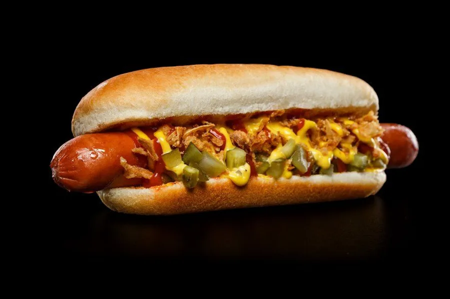 Perro caliente cargado con salsas, papa ripio y vegetales