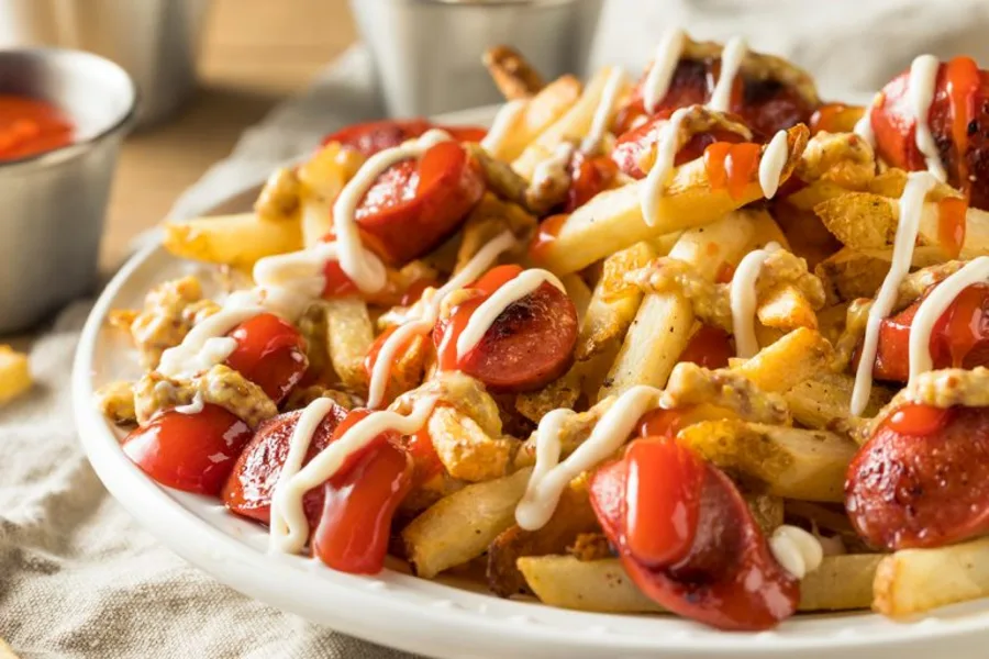 Salchipapas con salchicha en rodajas y salsas